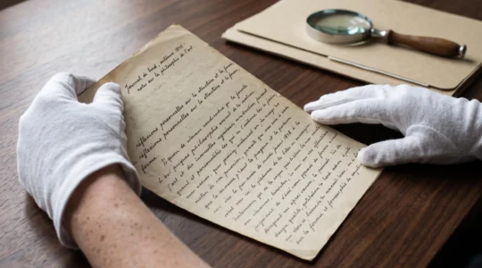 Mains gantées d'expert examinant un manuscrit original à l'encre sur table en bois sombre, éclairage latéral naturel révélant la texture du papier ancien